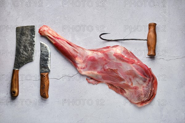 Overhead view of raw fresh deer leg with spice and herb over concrete background