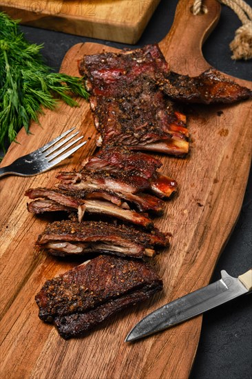 Top view of grilled lamb breast ribs on wooden cutting board