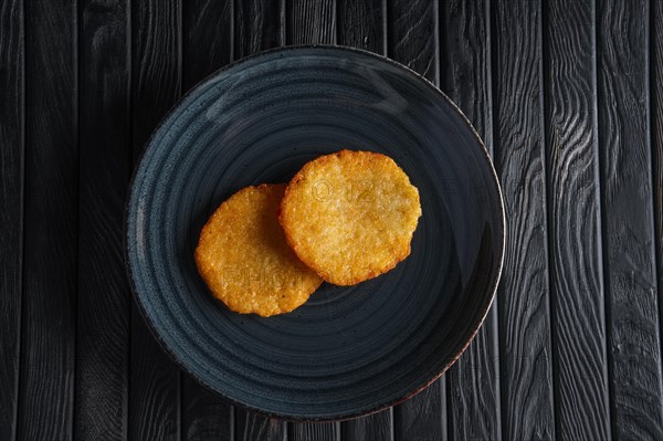 Portion of fried potato pancakes on dark wooden table