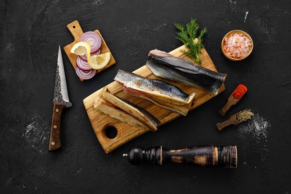 Raw fresh frozen herring carcass with spices on cutting board