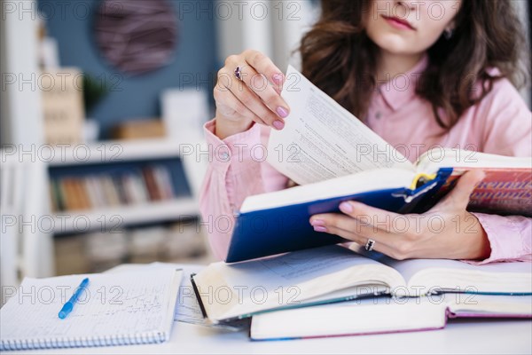 Crop woman reading textbooks library