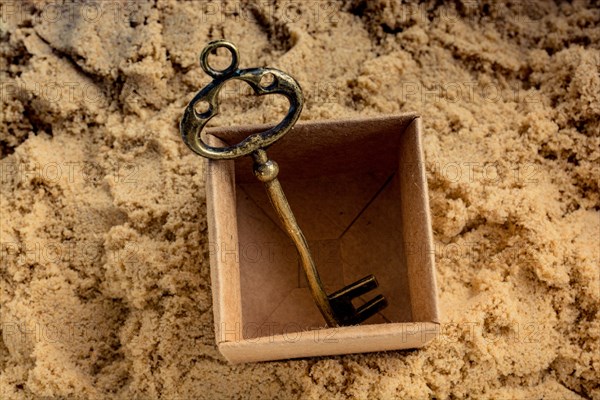 Retro style key placed in a brown box on sand