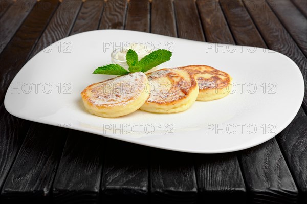 Cottage cheese fritters with sugar powder and sour cream