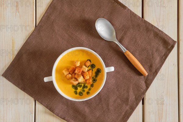 Top view of mashed peas soup with curry and crouton on wooden table