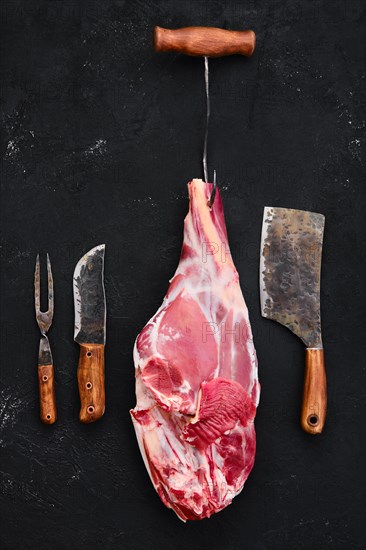 Fresh raw lamb leg bone in on wooden cutting board