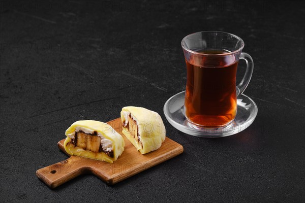 Sweet dessert mochi with banana and chocolate cut on half with fruit tea