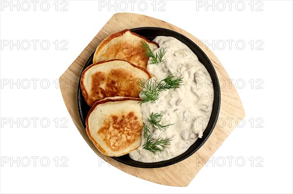 Flapjack with mushroom sauce on wooden plate. Top view