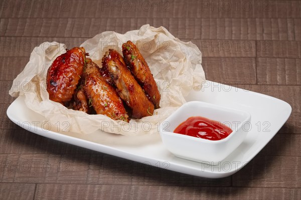 Closeup view of fried chicken wings with ketchup in wrapping paper
