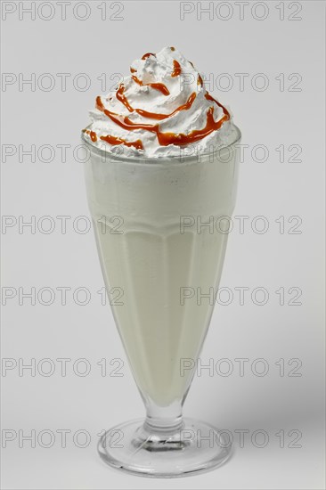 Melon and caramel milkshake summer cocktail in tall facetted glass on gray background