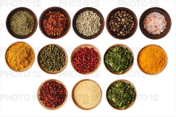 Various seasonings and herbs in bowls isolated on white background