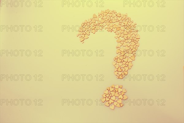 Wooden hearts form a question mark on a white background