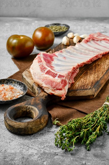 Raw fresh lamb breast and flap with ingredients on wooden cutting board