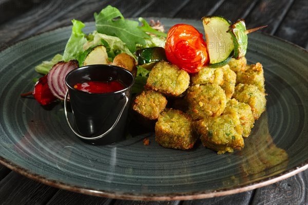Closeup view of fried falafel with grilled vegetables on wooden skewer