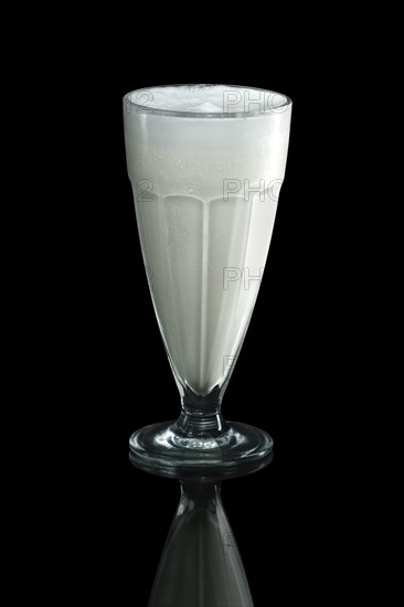 Glass of cold milk cocktail isolated on black
