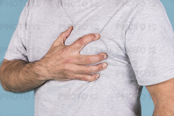 Close up man s hand holding his heart pain