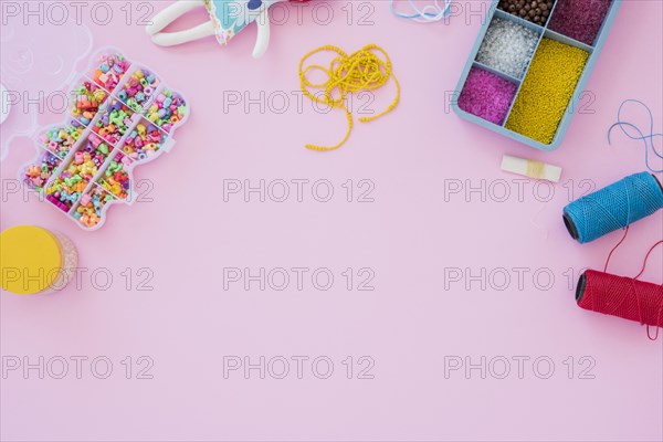 Colorful beads case yarn spools pink background