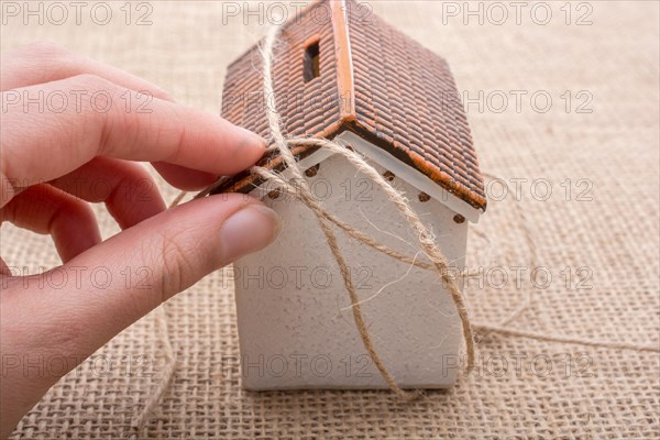 Thread wrapped around a model house on a brown background