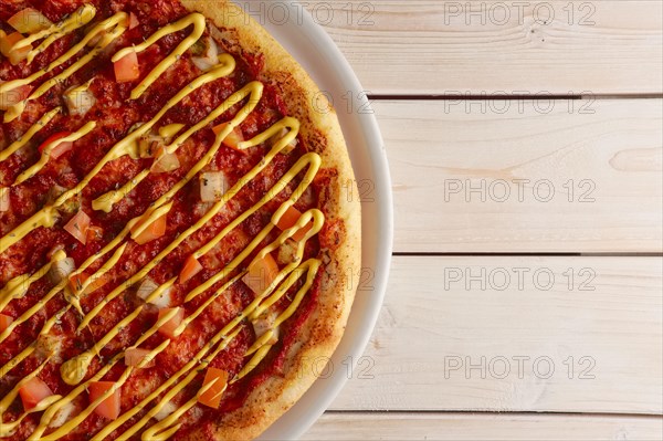 Top view of pizza with sun-dried tomatoes and mustard sauce