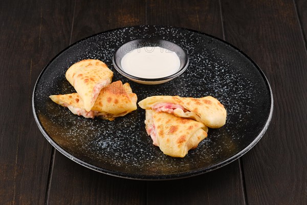 Thin crepe stuffed with ham and cheese cut on half