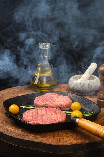Smoky raw beef burger patty on cast iron pan
