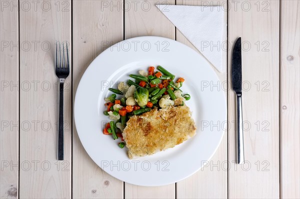 Top view of plate with fried fish and vegetables