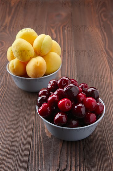 Cherries and apricots on dark wooden background