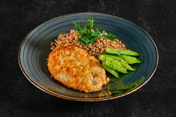 Top view of chicken fillet fried in batter with buckwheat porridge and pickled cucumber