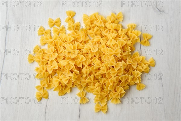 Top view of raw farfalle pasta with spice and herbs on wooden background