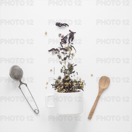 Tea herbs falling from cup with strainer spoon white backdrop. Resolution and high quality beautiful photo