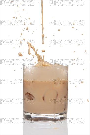 Irish creme liqueur pouring in a glass full of ice