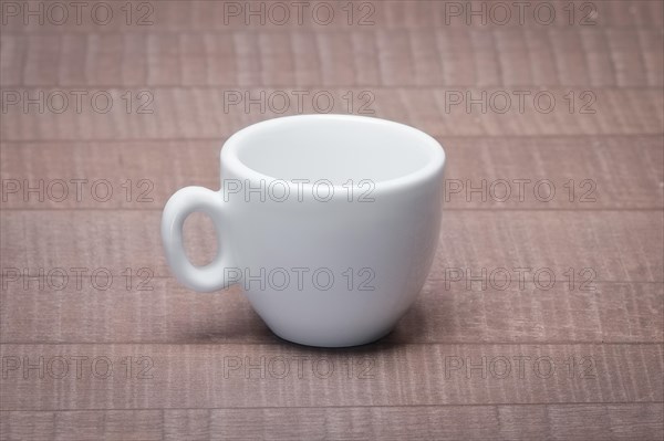 Clean and empty ceramic cup for espresso without saucer on wooden table