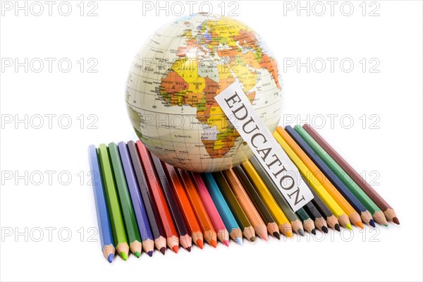 Colour pencils with globe and education note on them on a white background