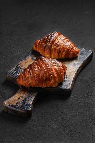 Crispy croissant on shabby wooden serving board