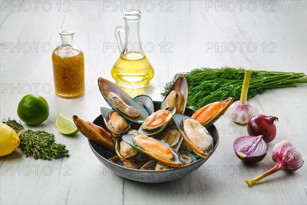 Plate with raw large mussels in half shell with spice on wooden table