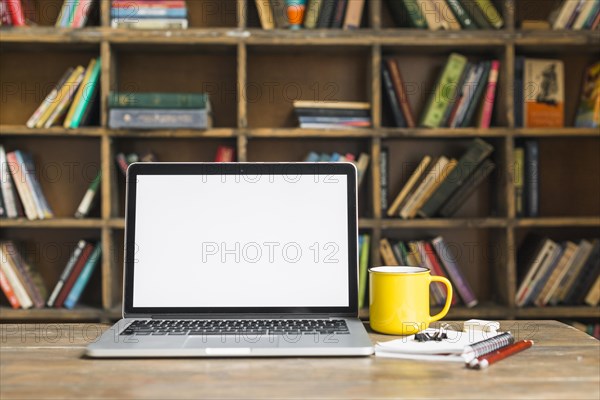 Coffee mug laptop with stationeries wooden desk library