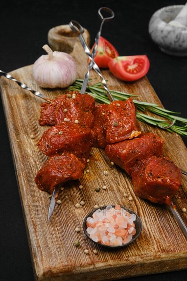 Marinated raw pork meat on skewer on dark background