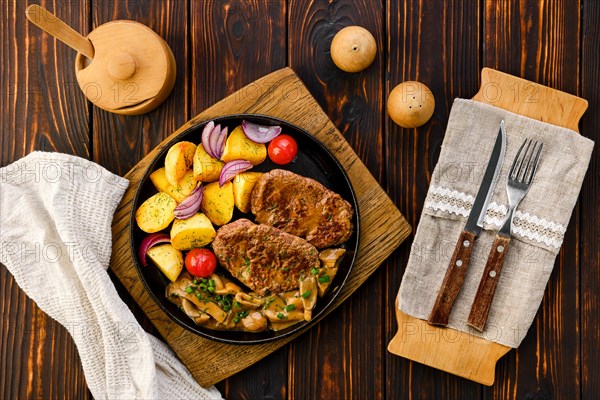 Top view of fried beef fillet with potato wedges served with fresh onion