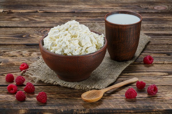 Cottage cheese and milk in clayware on wooden table