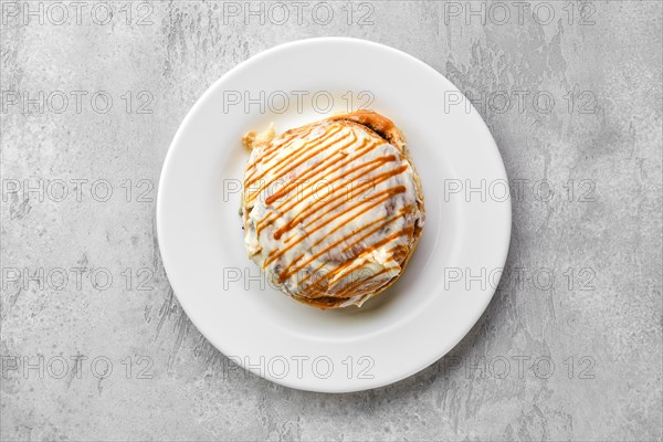 Top view of fresh cinnamon bun with sugar icing and caramel