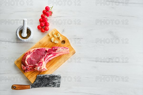 Beef ribeye steak bone-in with spice on wooden cutting board