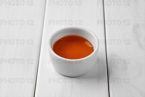 Honey in ceramic gravy boat on white wooden table