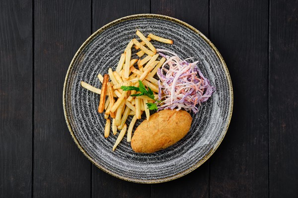 Top view of Kiev cutlet with american fries and red cabbage with carrot as a garnish