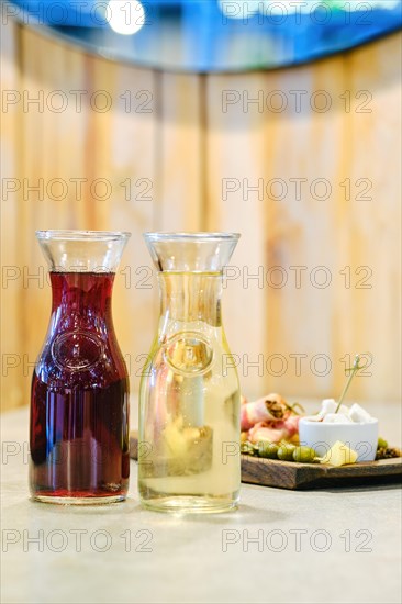 Two decanters with wine and plate with snack on background