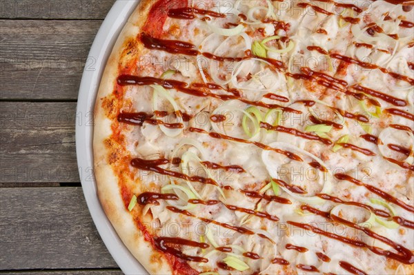 Top view of part of pizza with chicken barbecue on wooden table
