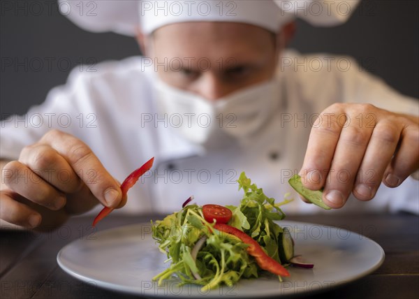 Close up chef with mask preparing dish