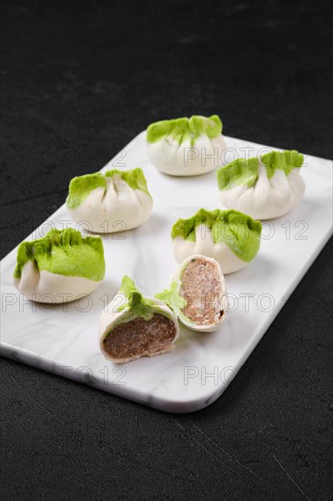 Frozen dumplings stuffed with pork meat and provencal herbs on marble serving plate