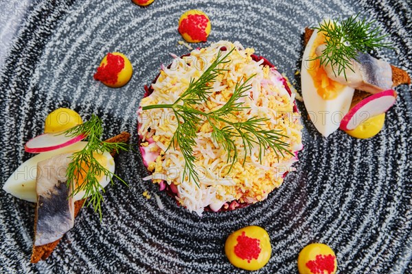 Close up view of herring layered salad decorated with a quarter of a boiled egg and a piece of herring