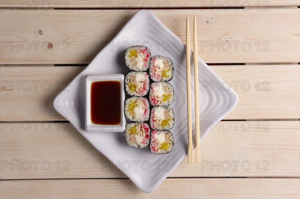 Rolls with eel and avocado on plate with soy sauce and hashi