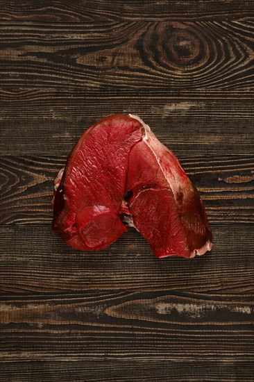 Overhead view of raw deer boneless ham over wooden background