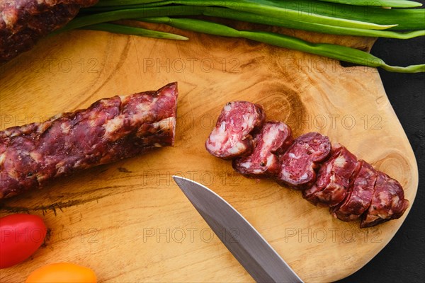 Close up view of dried pork sausage on wooden cutting board